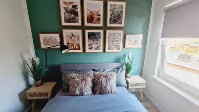 a bedroom with a blue bed with pictures on the wall at Beautiful 2bed house with garden, walking distance to town - FREE parking in Glasgow