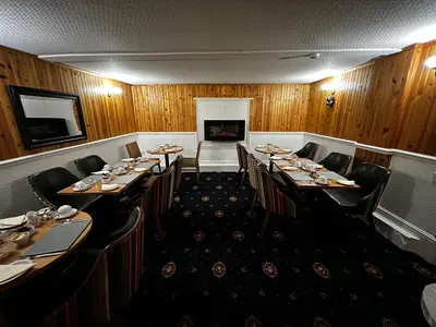 a dining room with tables and chairs and a fireplace at Dunarle Guesthouse in Oban