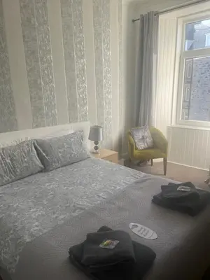 a bedroom with a bed and a chair and a window at Dunarle Guesthouse in Oban