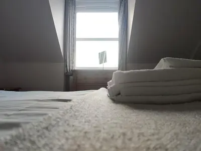 a pile of towels sitting on a bed with a window at Station View in Oban