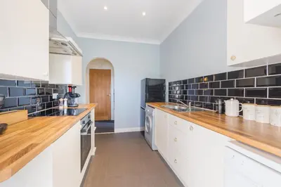 a large kitchen with white cabinets and black tiles at Beautiful 2 to 3 bed apartment with stunning views! in Ayr