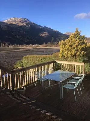a table and chairs on a deck with a view of a mountain at Viking Cottage in Arrochar