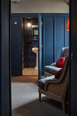 a room with a chair and a bathroom with a sink at No17 The Promenade in Oban