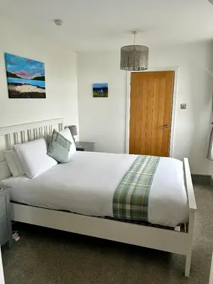 a bedroom with a large white bed and a wooden door at Lochaline Hotel in Lochaline