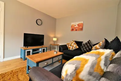 a living room with a couch and a flat screen tv at Signature - Whistleberry House in Hamilton