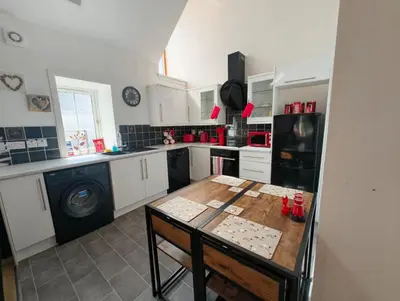 a kitchen with a wooden table and a stove at Doocot At Bonnyside House - New Hot Tub Aug 2025 in Bonnybridge