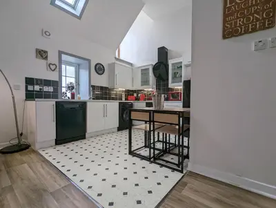 a kitchen with white cabinets and a table in it at Doocot At Bonnyside House - New Hot Tub Aug 2025 in Bonnybridge