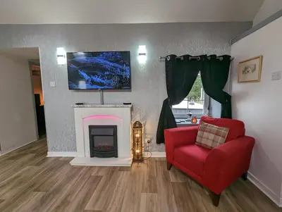 a living room with a red chair and a fireplace at Doocot At Bonnyside House - New Hot Tub Aug 2025 in Bonnybridge
