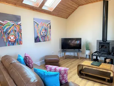 a living room with a couch and a flat screen tv at Partridge Lodge with Hot Tub in Forgandenny