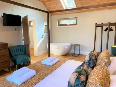 a bedroom with a tub and a bed and a television at Partridge Lodge with Hot Tub in Forgandenny