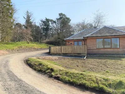 a house on the side of a dirt road at Partridge Lodge with Hot Tub in Forgandenny