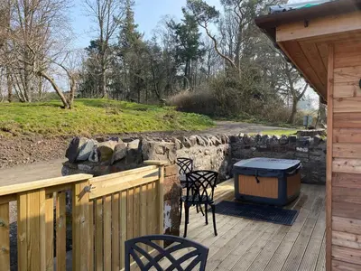 a wooden deck with chairs and a trash can on it at Partridge Lodge with Hot Tub in Forgandenny