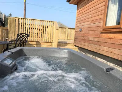 a hot tub on the patio of a house at Pheasant Lodge with Hot Tub in Forgandenny
