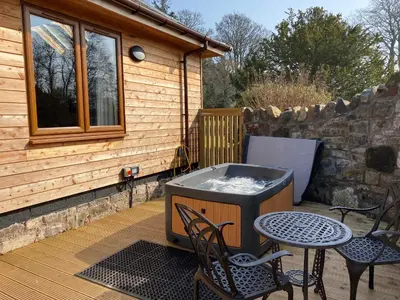 a hot tub on a deck with a table and chairs at Pheasant Lodge with Hot Tub in Forgandenny