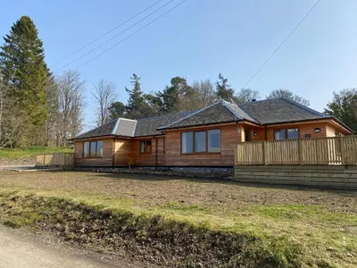 a log home with a porch and a deck at Pheasant Lodge with Hot Tub in Forgandenny