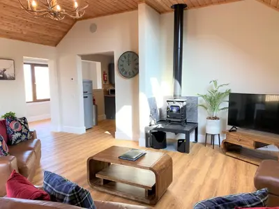 a living room with a couch and a tv at Pheasant Lodge with Hot Tub in Forgandenny