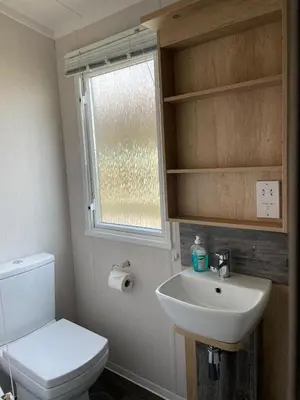 a bathroom with a toilet and a sink and a window at Swift Bordeaux 73 in Dunoon