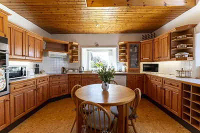a kitchen with wooden cabinets and a wooden table with chairs at East Kelt Farm Cottage in Denny