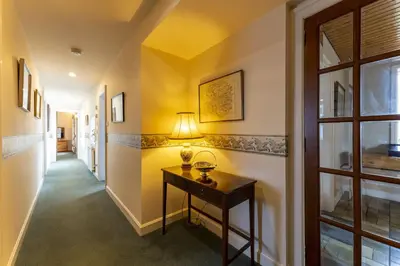 a hallway with a table with a lamp on it at East Kelt Farm Cottage in Denny