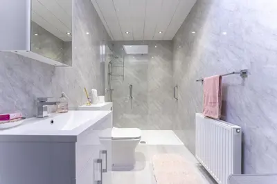 a bathroom with a sink and a toilet and a shower at East Kelt Farm Cottage in Denny