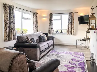 a living room with a couch and two windows at Ballygroggan Bungalow - Uk38174 in Machrihanish
