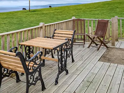 a table and two chairs on a deck with a table and benches at Ballygroggan Bungalow - Uk38174 in Machrihanish