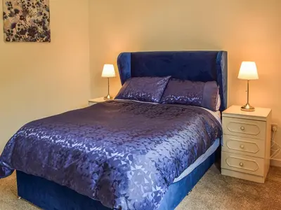 a bedroom with a blue bed and two night stands at Gleaner Lea Apartment in Campbeltown