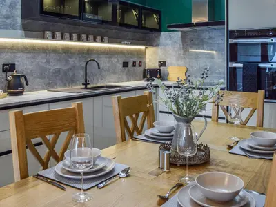 a kitchen with a wooden table with a vase of flowers at Gleaner Lea Apartment in Campbeltown