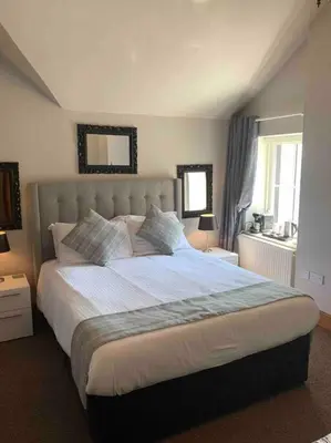 a bedroom with a large bed and two windows at The Apartment - Chandlers in Ascog