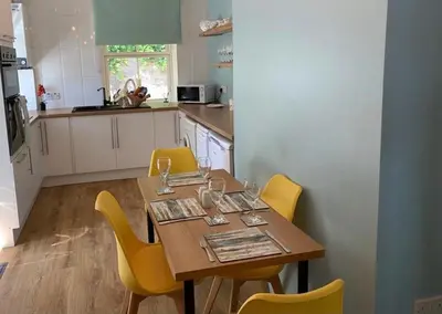 a kitchen with a wooden table and yellow chairs at Seaview Cottage Bute in Ascog