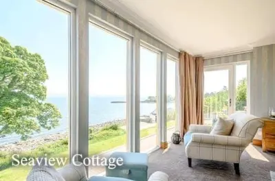 a living room with large windows and a couch at Seaview Cottage Bute in Ascog