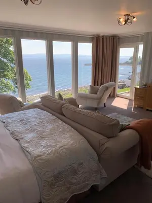 a bedroom with a large bed with a view of the ocean at Seaview Cottage Bute in Ascog