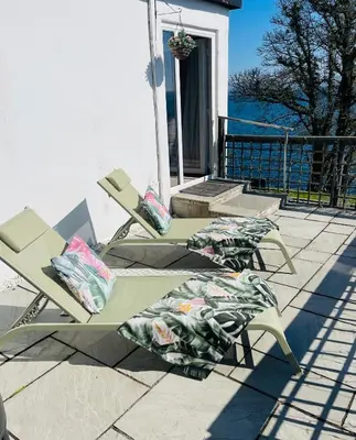 two lawn chairs with pillows sitting on a patio at Seaview Cottage Bute in Ascog
