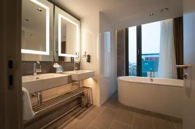 a bathroom with two sinks and a tub and a large window at Clayton Hotel Glasgow City in Glasgow