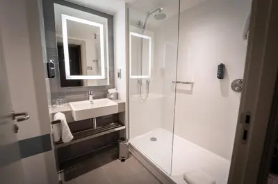 a white bathroom with a sink and a shower at Clayton Hotel Glasgow City in Glasgow