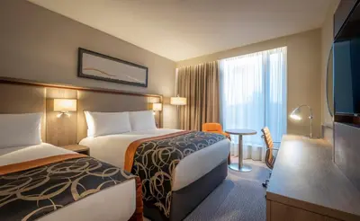 a hotel room with two beds and a television at Clayton Hotel Glasgow City in Glasgow