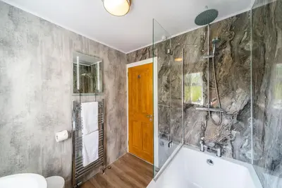 a bathroom with a tub and a glass shower at Lagnaha Cottage in Kentallen