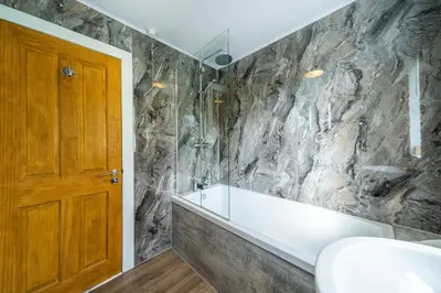 a bathroom with a stone wall at Lagnaha Cottage in Kentallen