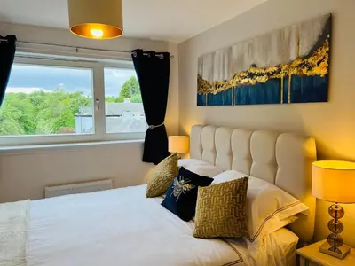a bedroom with a white bed and a window at Riverside View Penthouse in Balloch, Loch Lomond in Balloch
