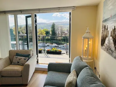 a living room with a couch and chairs and a large window at Riverside View Penthouse in Balloch, Loch Lomond in Balloch