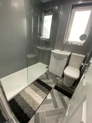 a bathroom with a toilet and a glass shower at Pure Apartments Fife - Dunfermline West in Oakley