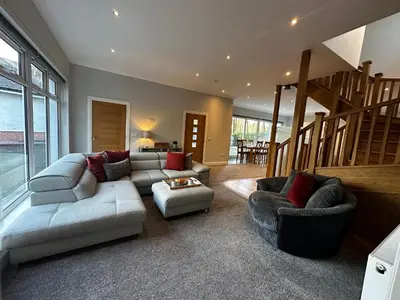 a living room with a couch and chairs and a staircase at The Buckie at Buchanan - Drymen Holiday Home Sleeps 8 in Drymen