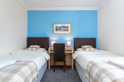 a room with two beds and a desk with a chair at NEW Four Bedroom House - all rooms ensuite in Stirling