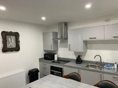 a kitchen with white cabinets and a clock on the wall at Tanllan Apartment in Callander