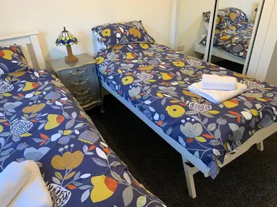a bedroom with two beds and a mirror at Tanllan Apartment in Callander