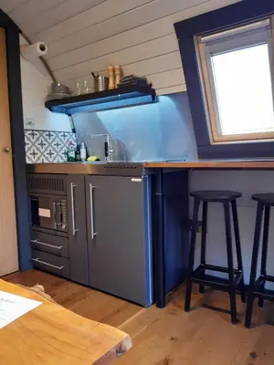 a kitchen with a stove and a counter with stools at Riverside Pod, West Highland Way Holidays in Kinlochleven