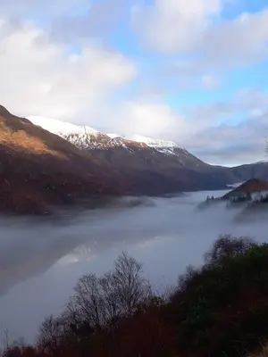 a view of a body of water with snow covered mountains at Riverside Pod, West Highland Way Holidays in Kinlochleven