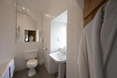 a white bathroom with a toilet and a sink at Stables Cottage in Perth