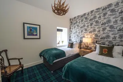 a hotel room with two beds and a chair at Stables Cottage in Perth