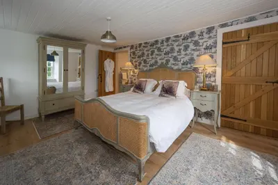 a bedroom with a large bed with white sheets and pillows at Laverockbank Farmhouse in Perth